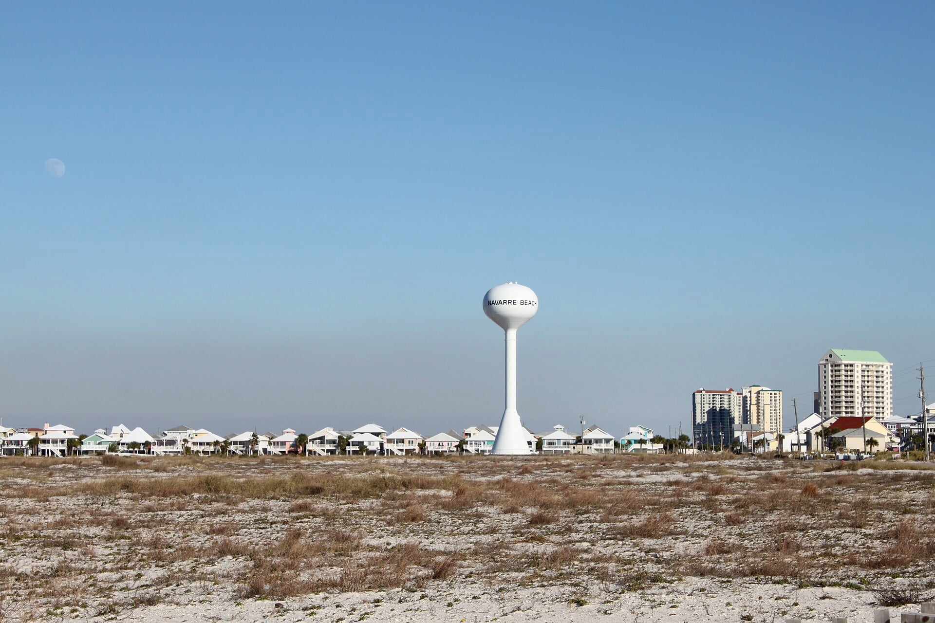The white Navarre Beach water tower above low dunes and beach houses