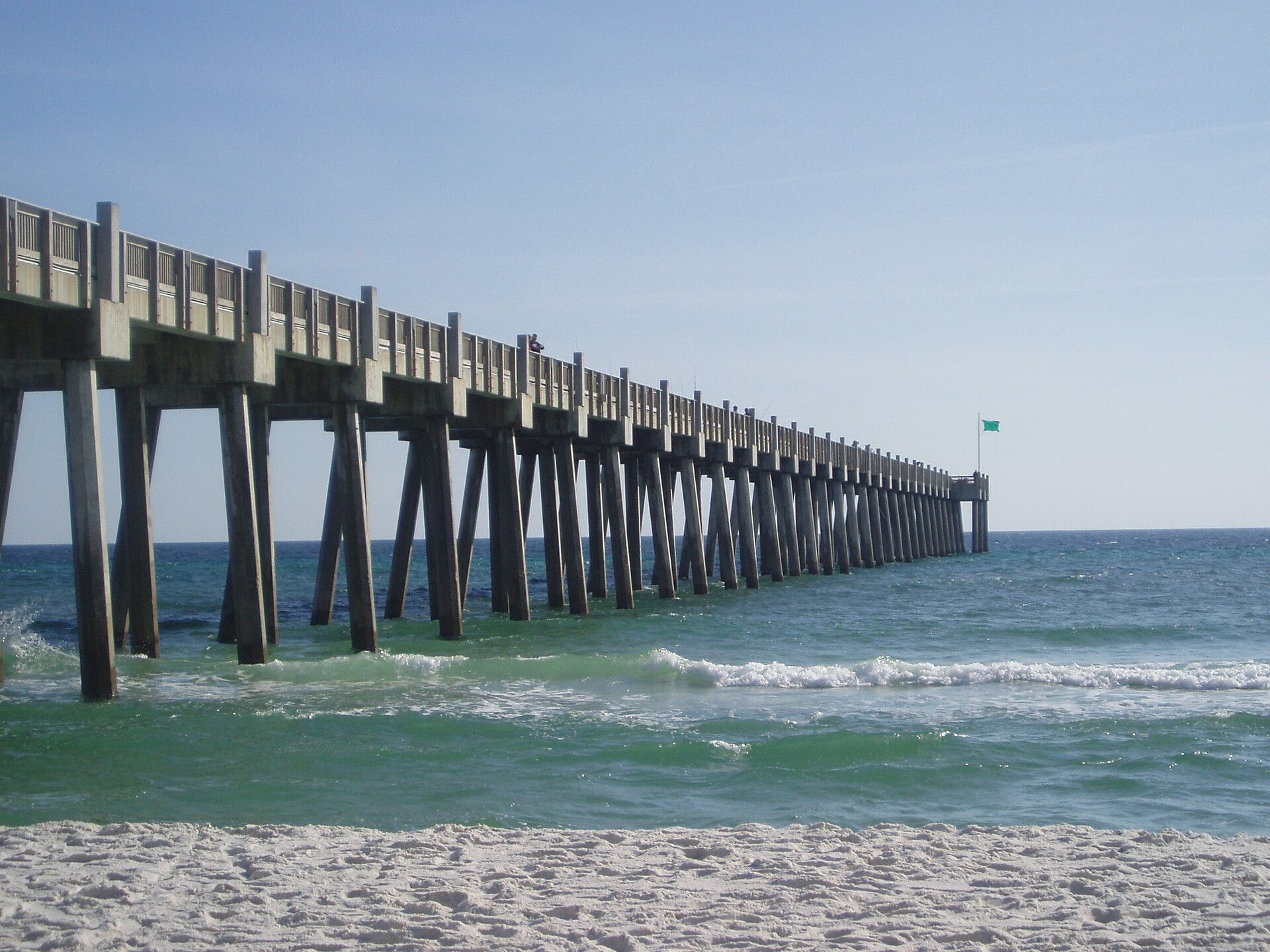The long concrete Gulf Pier stretching out over green water at Pensacola Beach