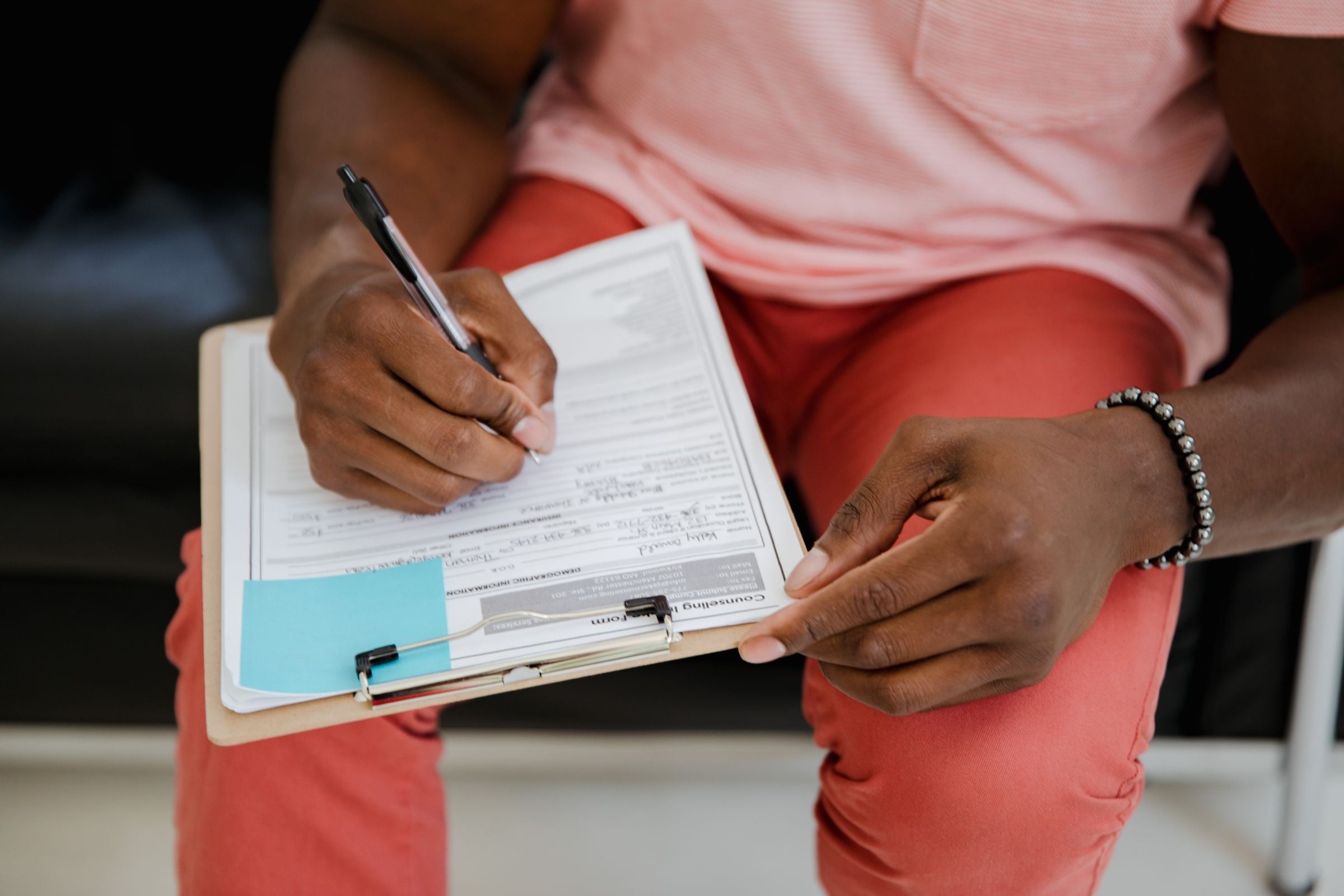 A hand filling in a job application form on a clipboard