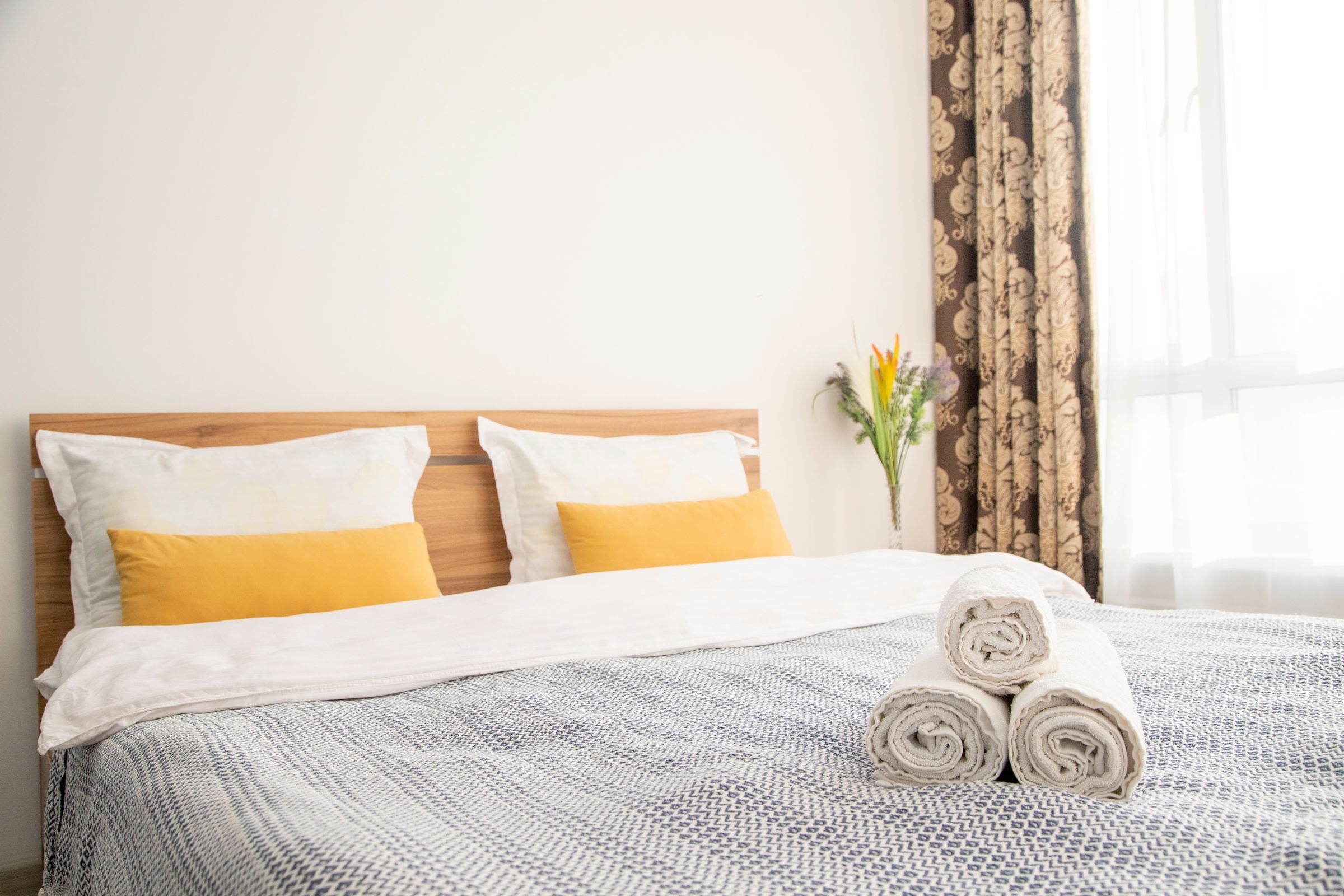 A bright hotel room with fresh bedding and rolled towels