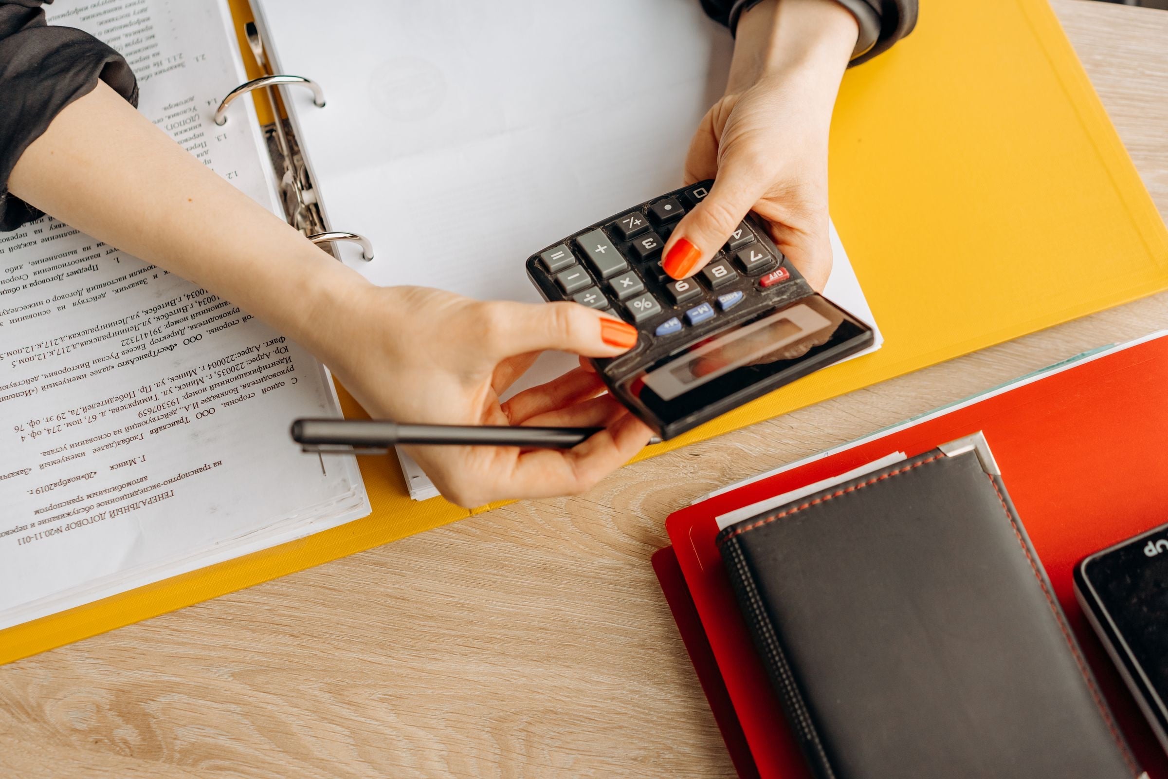 Hands on a calculator beside a folder of pay documents