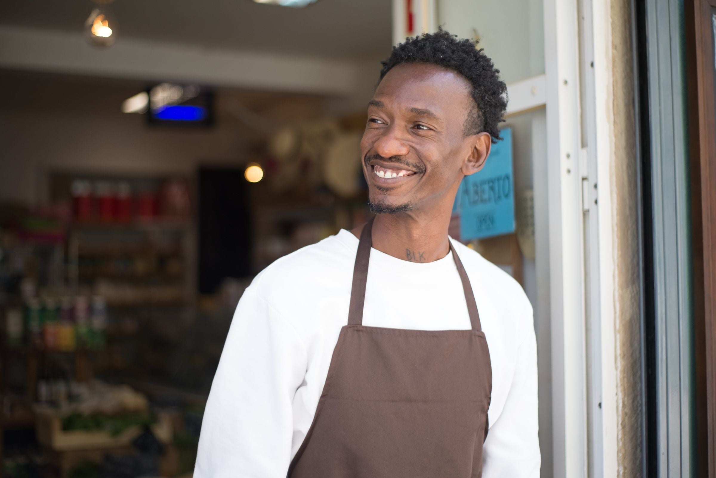 A smiling store associate in an apron at a shop entrance