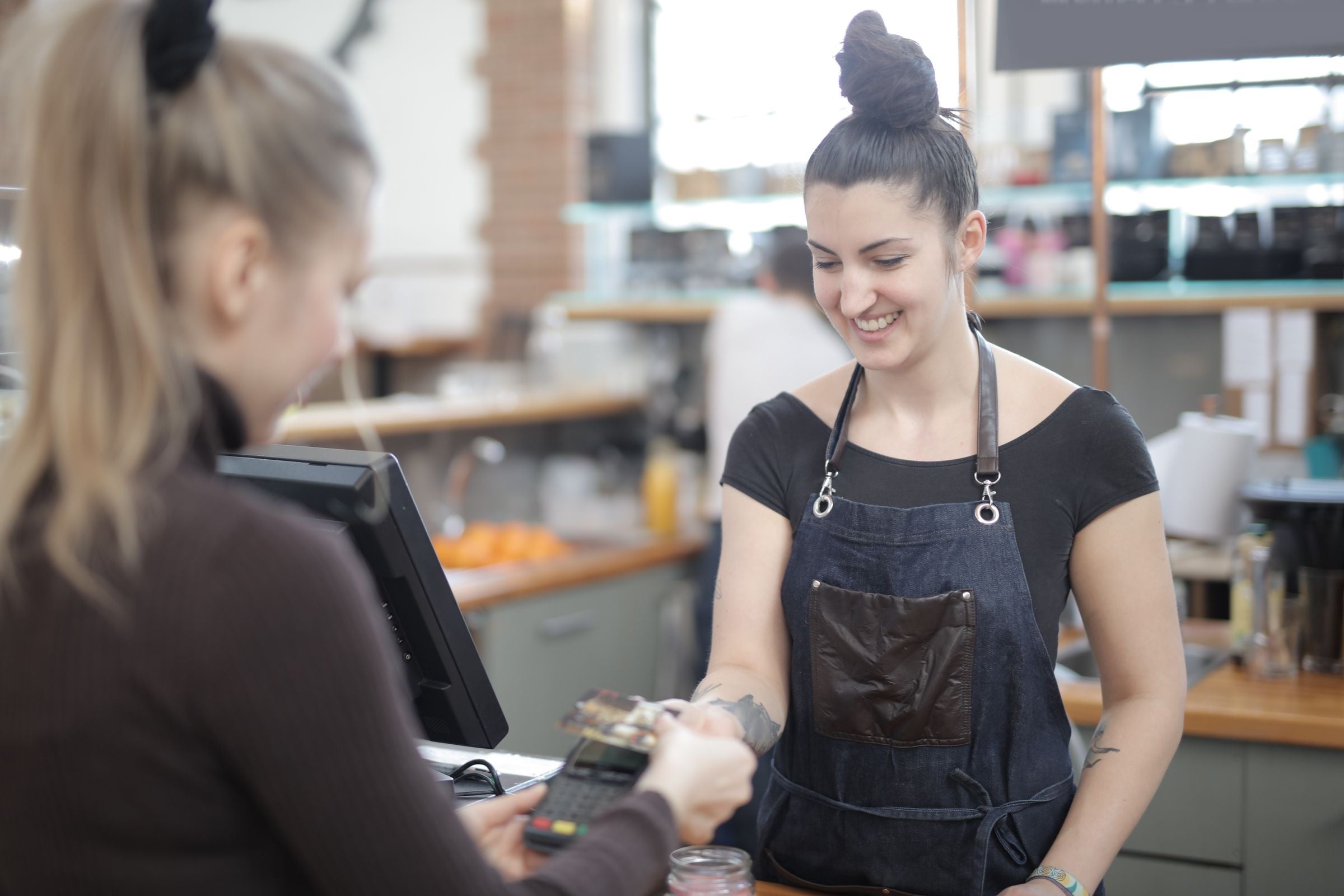 A smiling cashier helping a customer pay at a store counter
