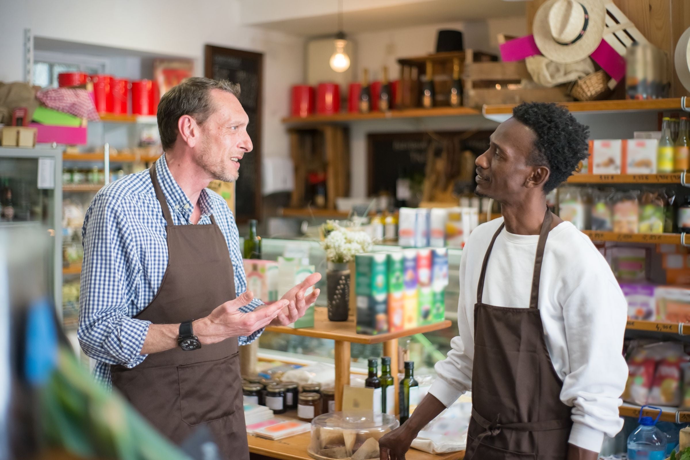 Two grocery associates talking in a store aisle