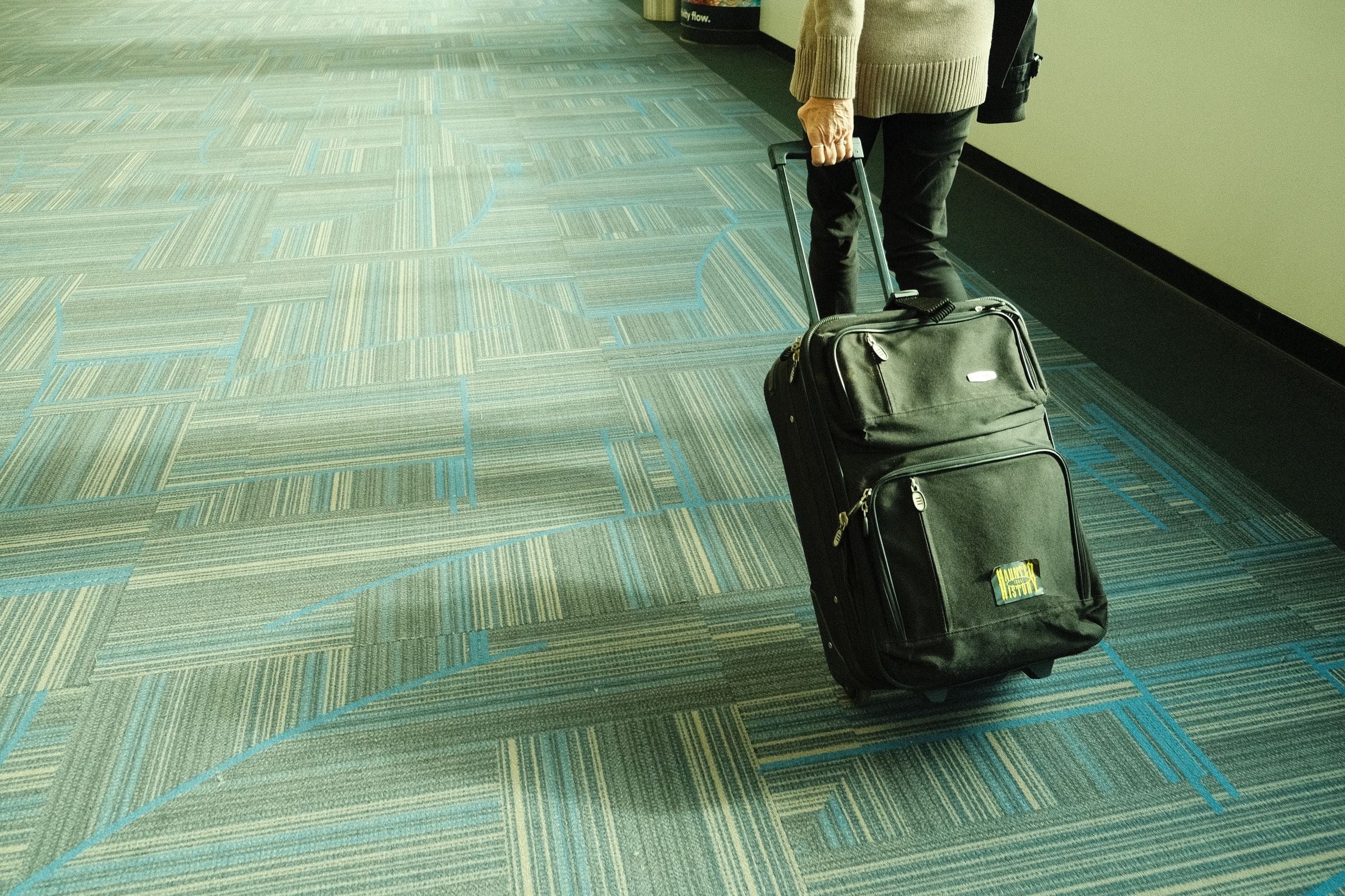 A traveler walking through an airport corridor with a suitcase