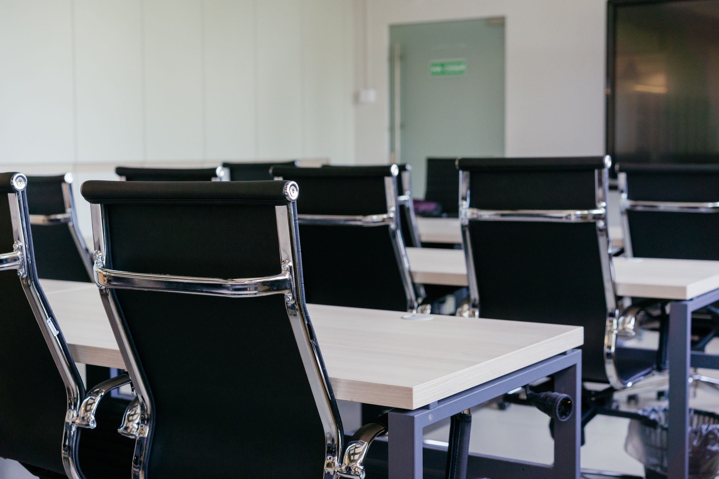 A modern meeting room with black chairs and white desks