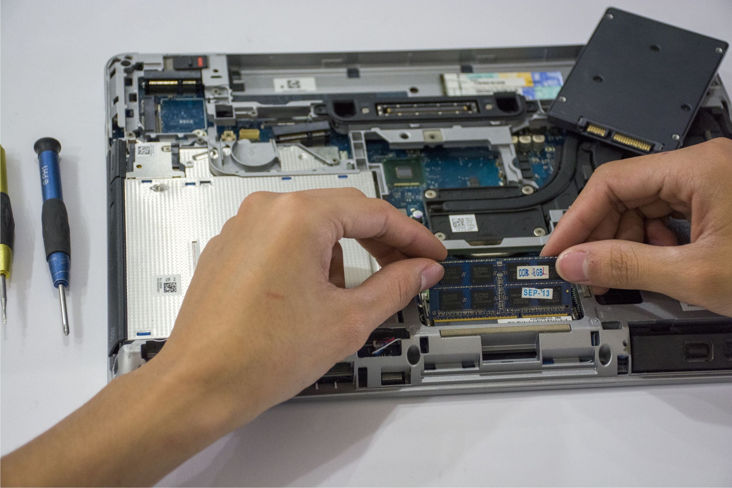 A technician’s hands working inside an open laptop